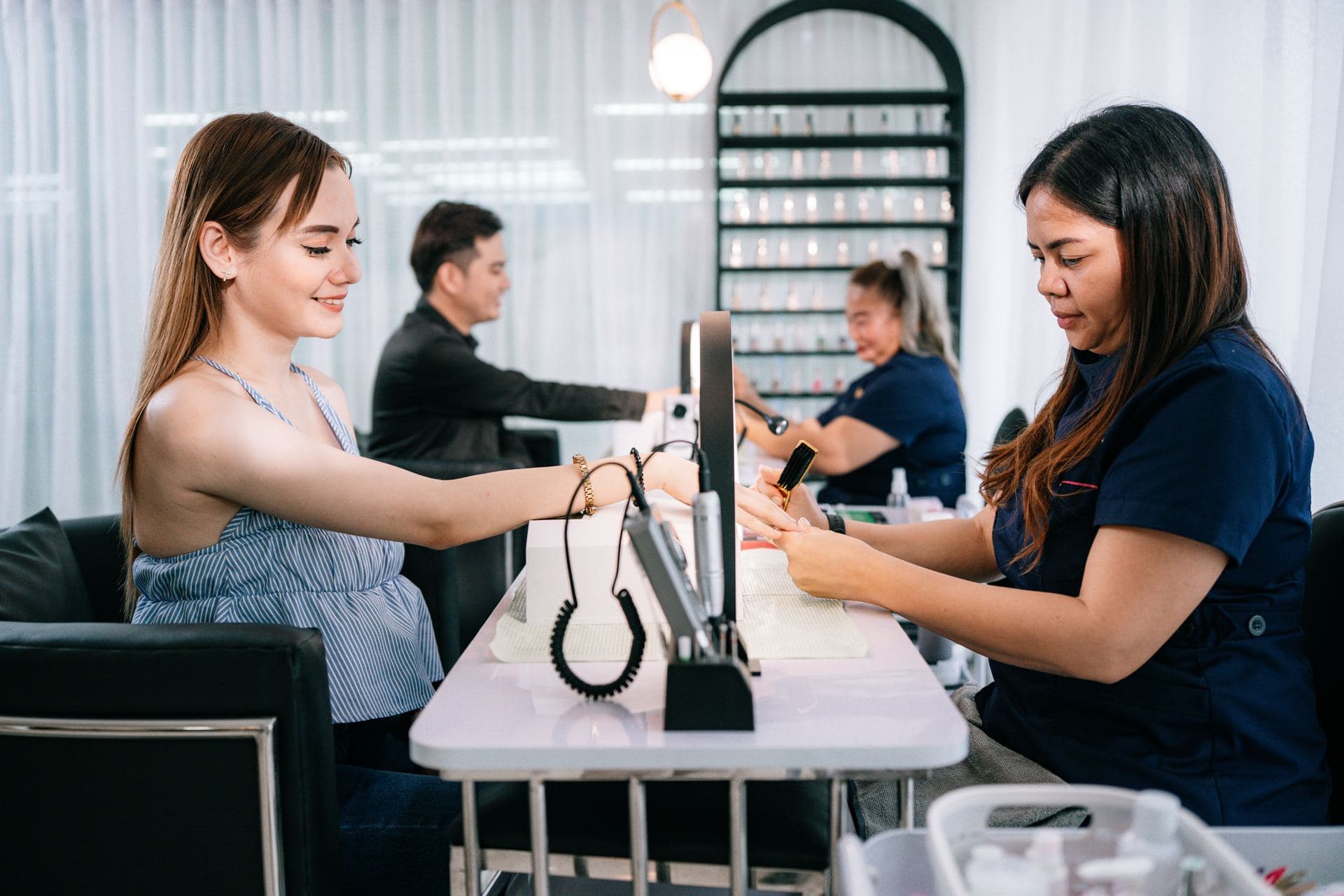 Nail technician performing a manicure at a marble station
