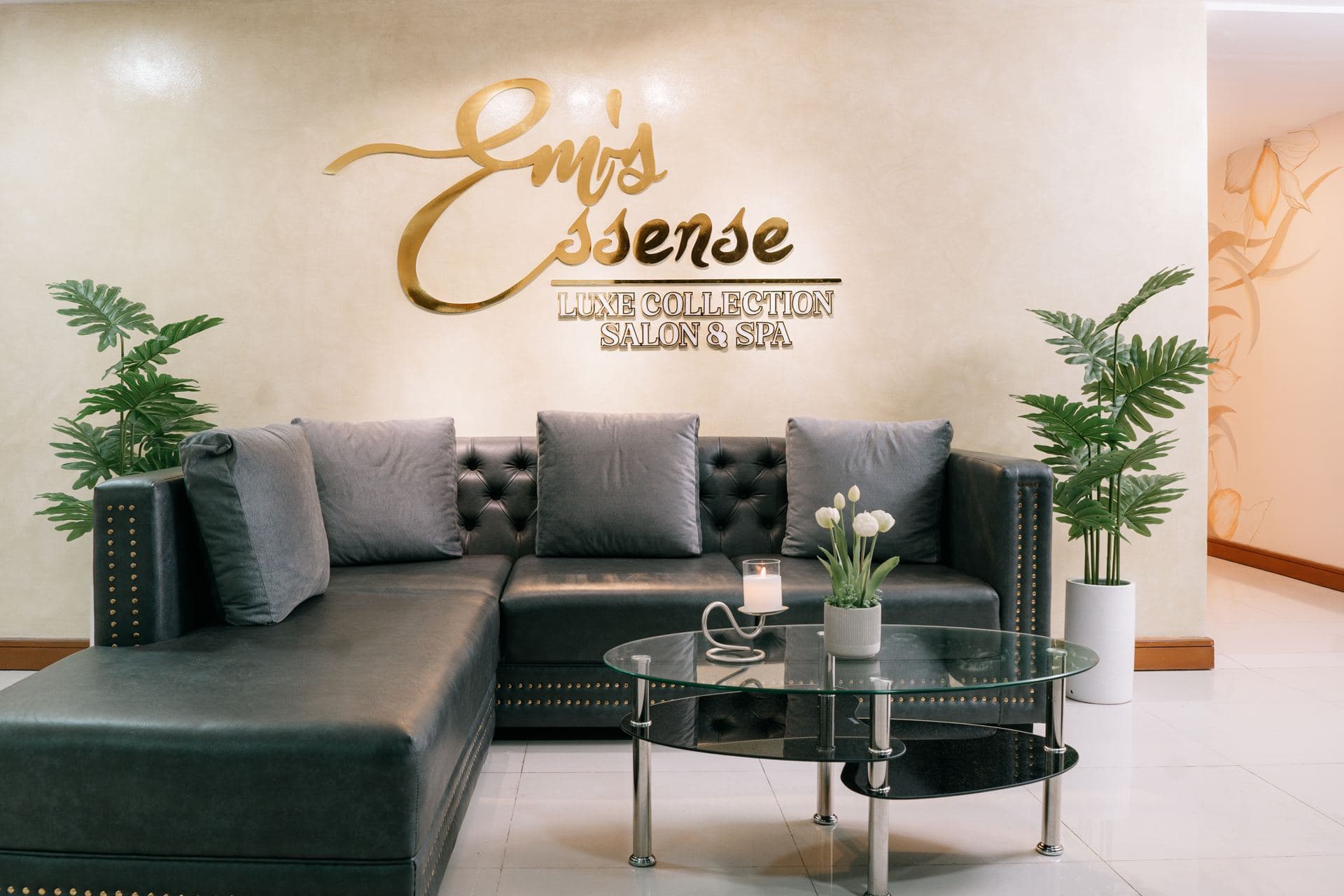 The Em’s Essense waiting lounge with a plush sofa beneath the gold signage